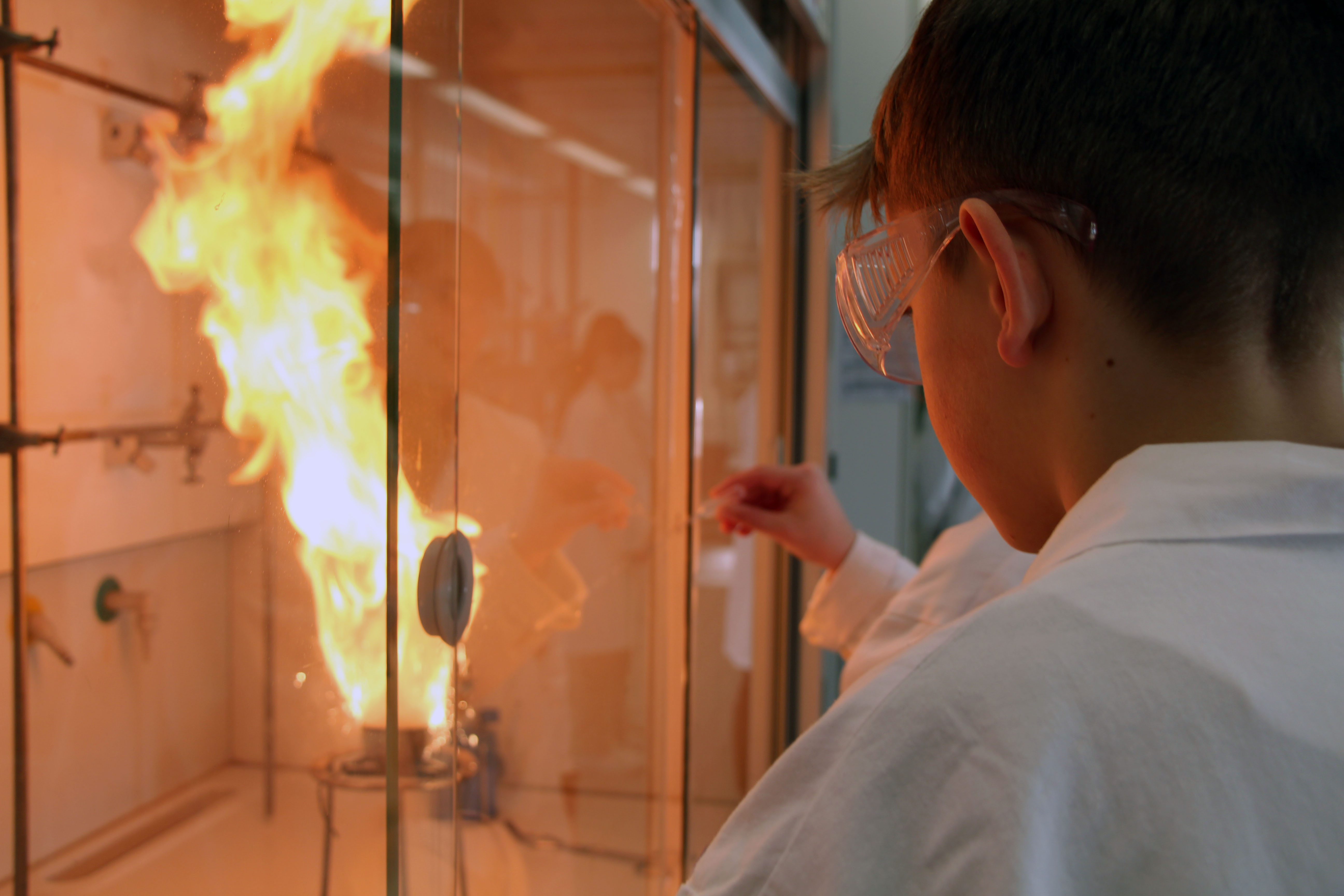 Schüler*innen experimentieren mit Feuer und Flamme unter dem Abzug im Labor