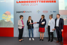 Dr. Ute Krupp (Henkel AG & Co. KGaA, Mitte) überreicht Vanessa Blacha (Vertretung von Sabine Timmermann, Bayer AG, 2.v.l.), im Beisein von Prof. Dr. Katrin Sommer (Ruhr-Universität Bochum, 1.v.l.), Katarina Keck (geschäftsführende Vorständin von „Jugend forscht“, 2.v.r.) und Dr. Carsten Penz (Landeswettbewerbsleiter von „Jugend forscht“ in NRW, 1.v.r.), den Staffelstab für die Ausrichtung des NRW-Landeswettbewerbs von  „Jugend forscht“ 2025. © Henkel AG & Co. KGaA