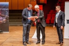 Dr. Nico Kock verleiht Christian Reiners (Luise-von-Duesberg-Gymnasium, Kempen), im Beisein von Dr. Carsten Penz, den Sonderpreis für die Projektbetreuenden. © RUB, Marquard